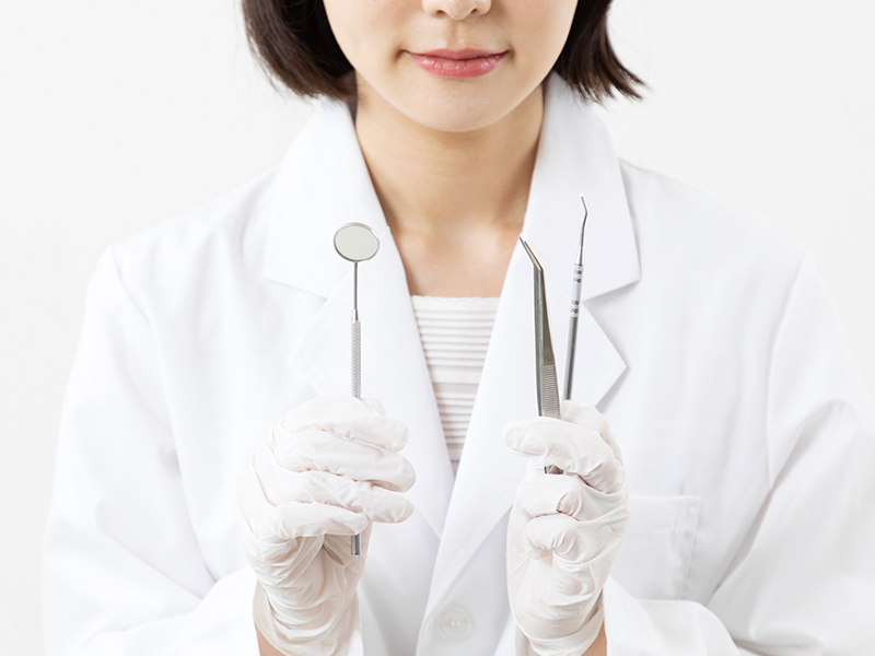 治療器具を持つ歯科衛生士
